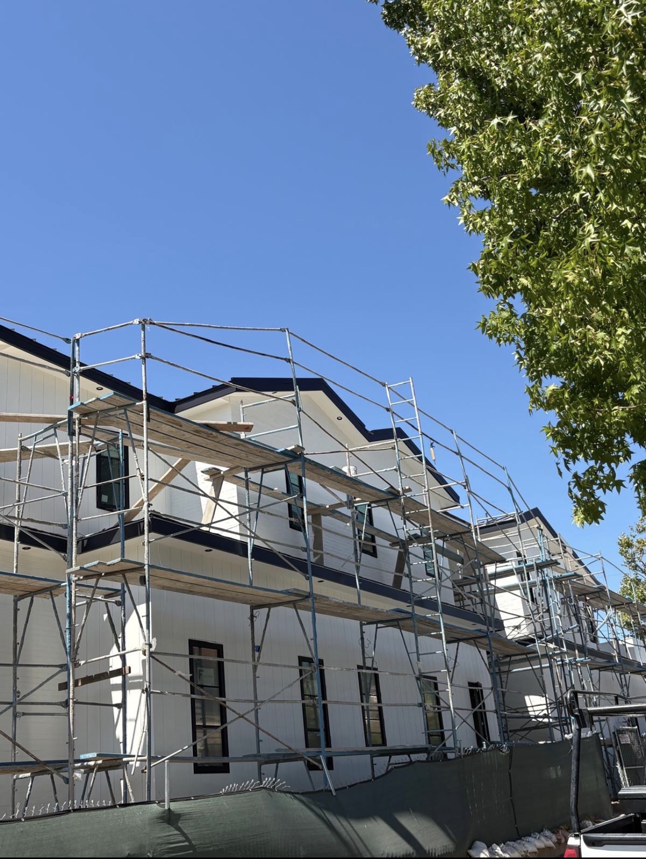 Multi-unit residential building with new dark metal roof edge and scaffolding during a large re-roof project