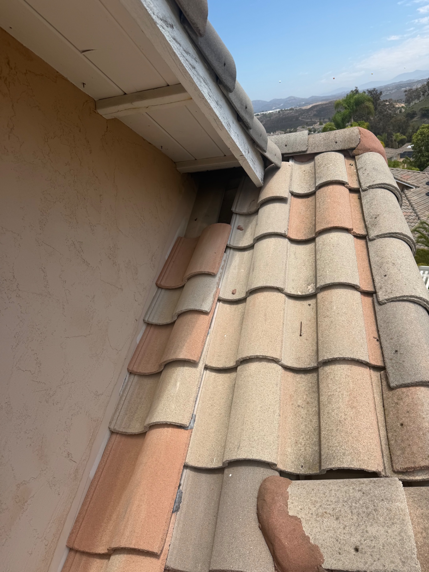 Displaced roof tiles at a rake edge exposing the batten gap next to fascia on a San Diego home