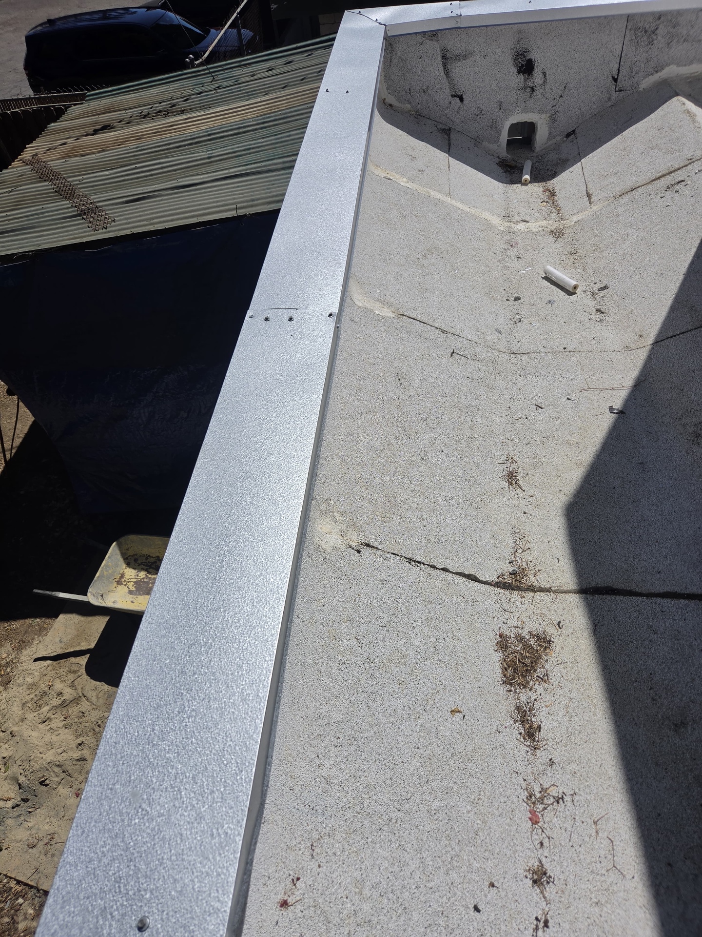 New galvanized coping metal along a parapet wall above a cap sheet flat roof