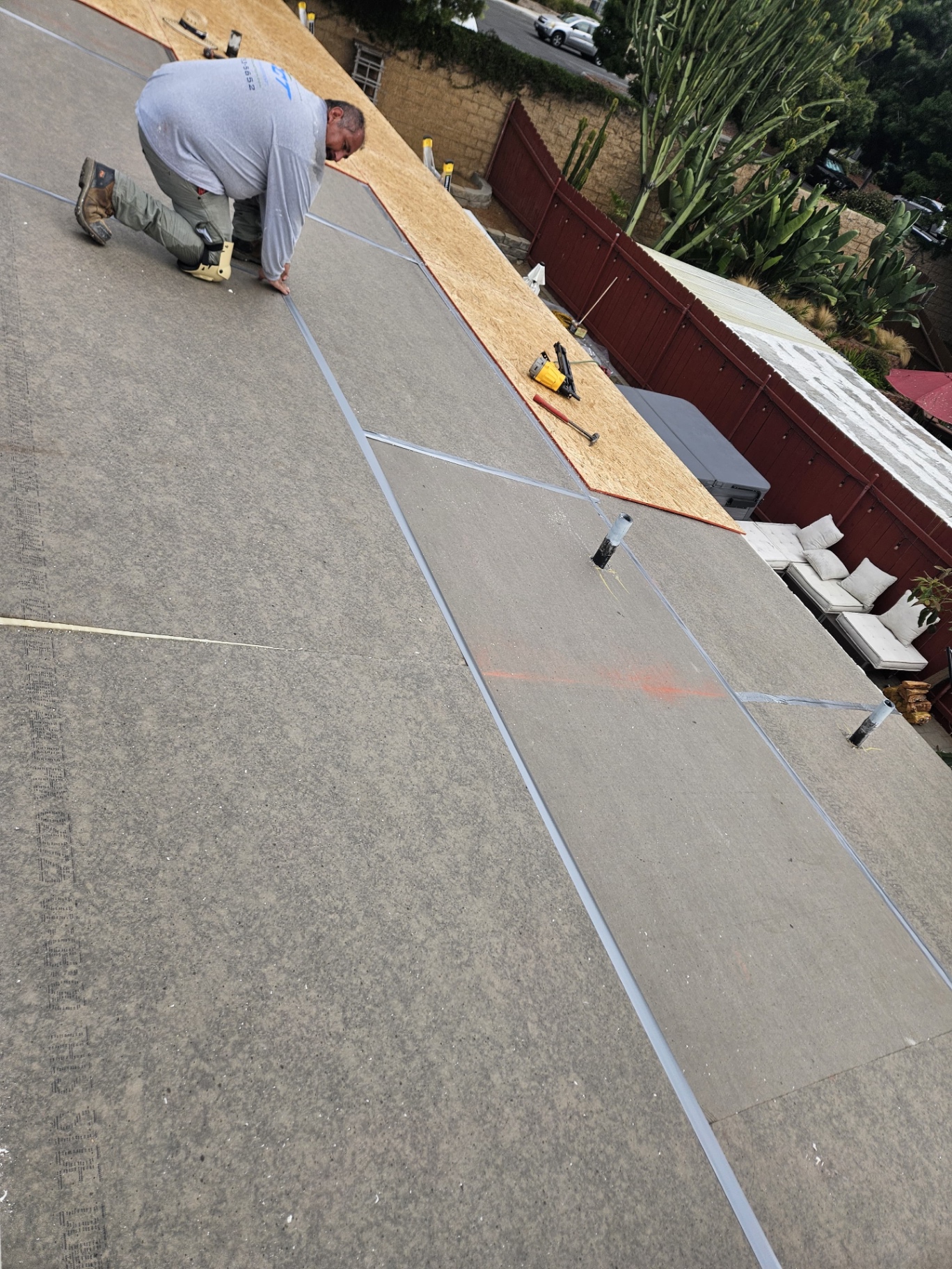 Roofer sealing polyiso insulation board joints on a low-slope roof in San Diego
