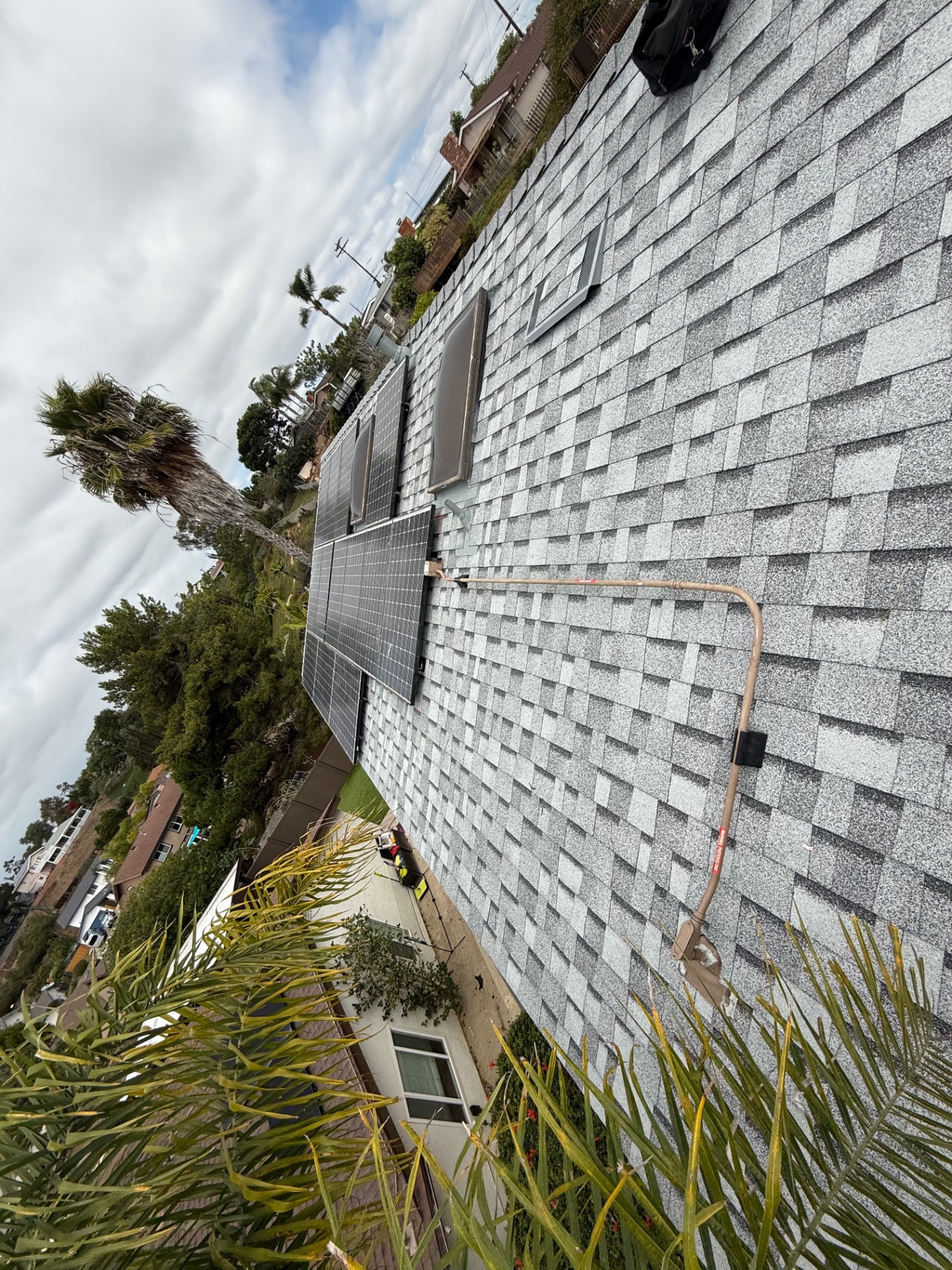 Solar panels reinstalled on a complete gray shingle roof replacement in San Diego