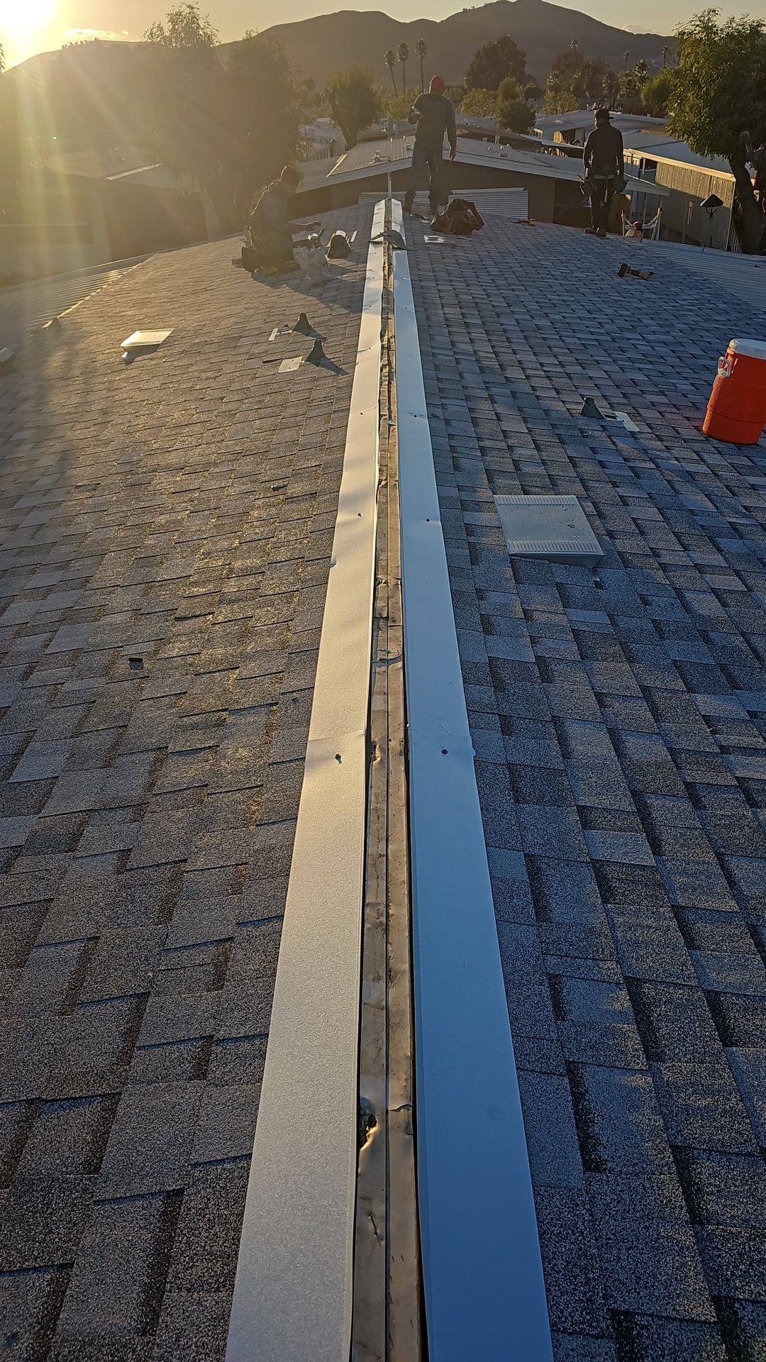 Ridge vent run down the full length of a San Diego shingle roof at sunset