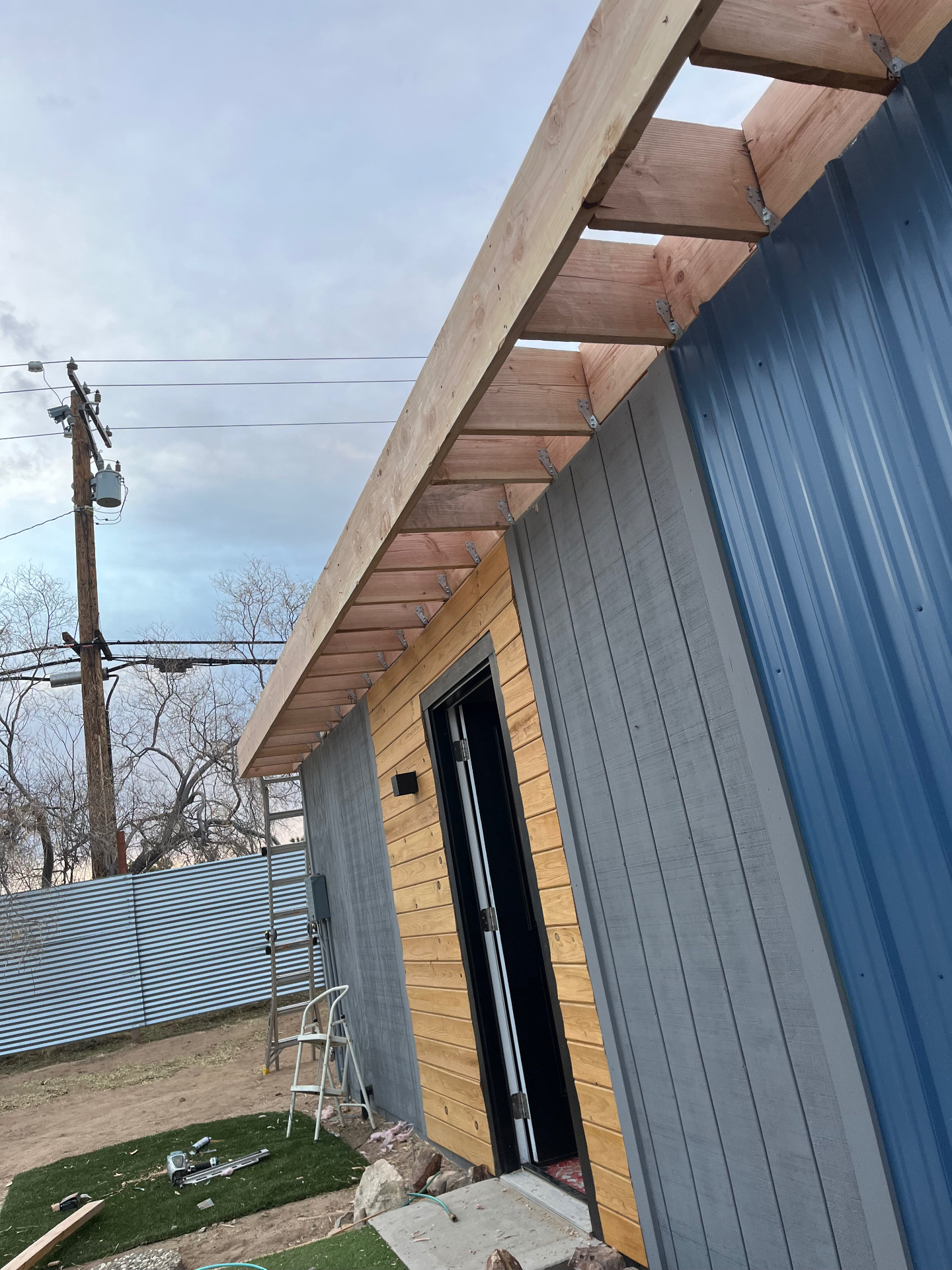 Wood framing and overhang extension along a metal-sided structure by California First Roofing