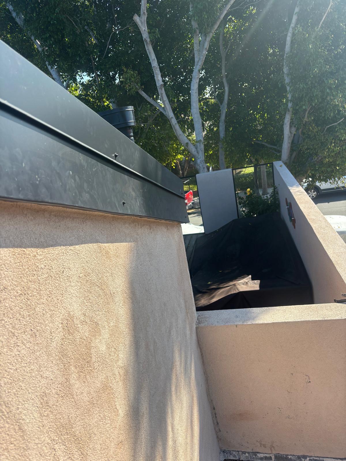 Metal fascia installed around a stucco skylight well and roof vent
