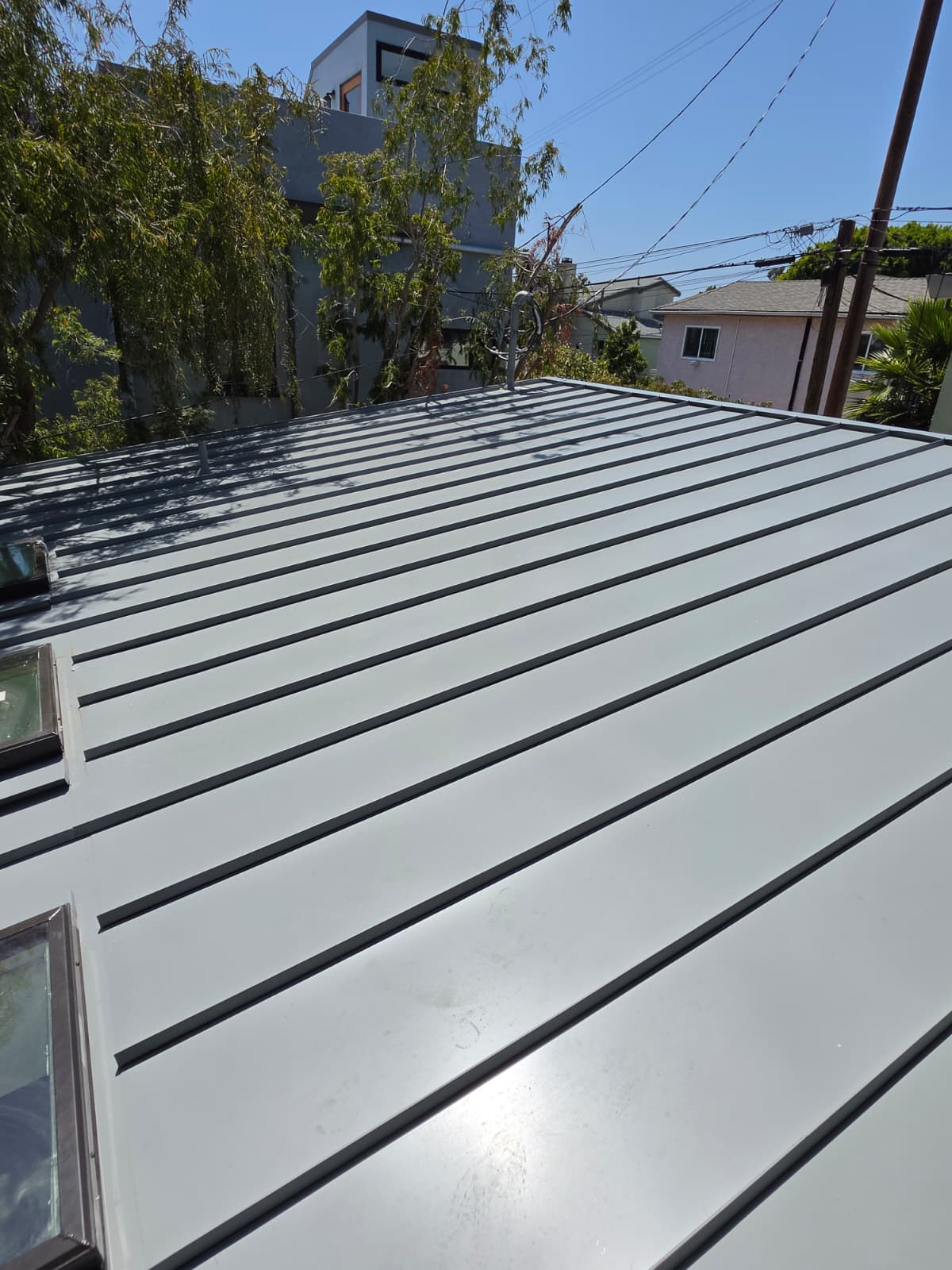 Completed light gray standing seam metal roof with skylights on a San Diego home