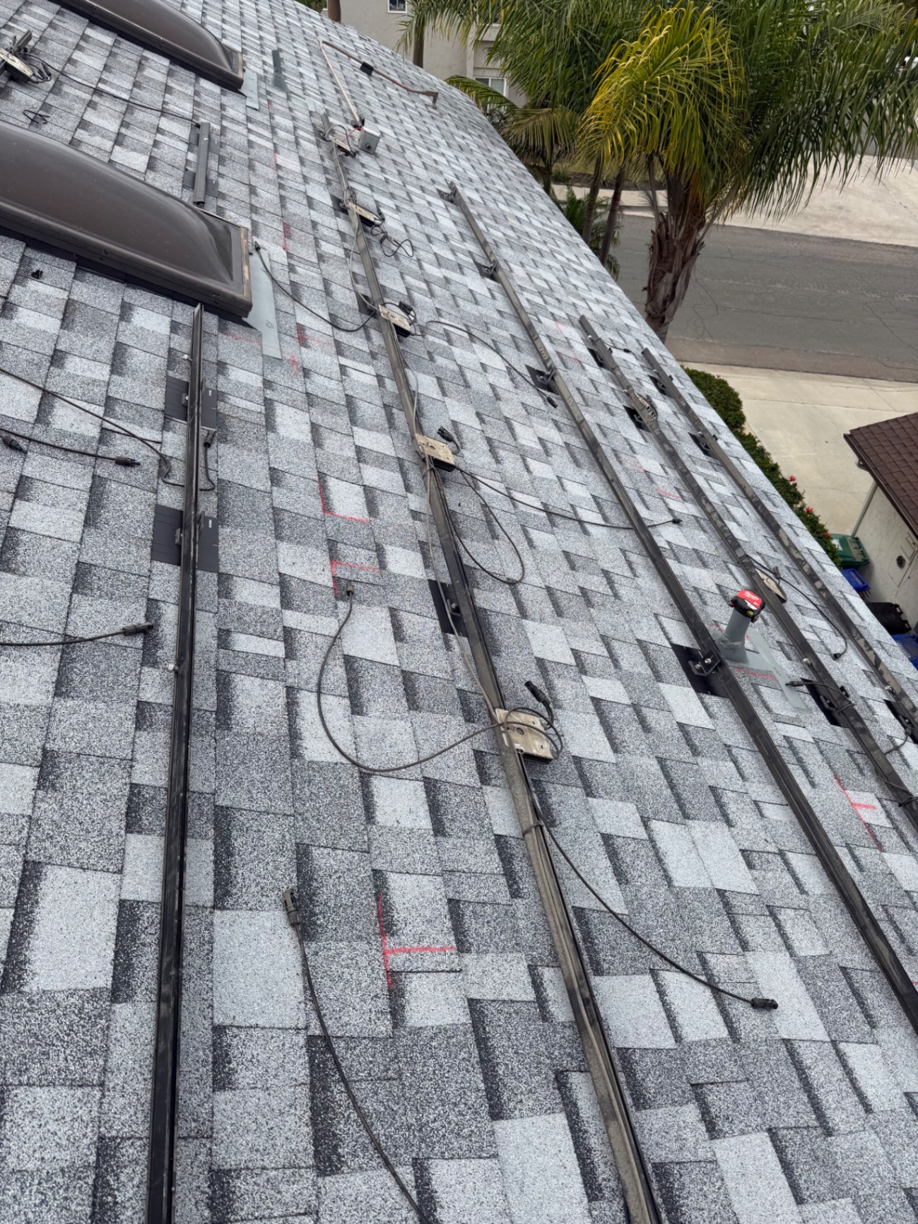 Solar rails being reinstalled over new gray architectural shingles on a San Diego home