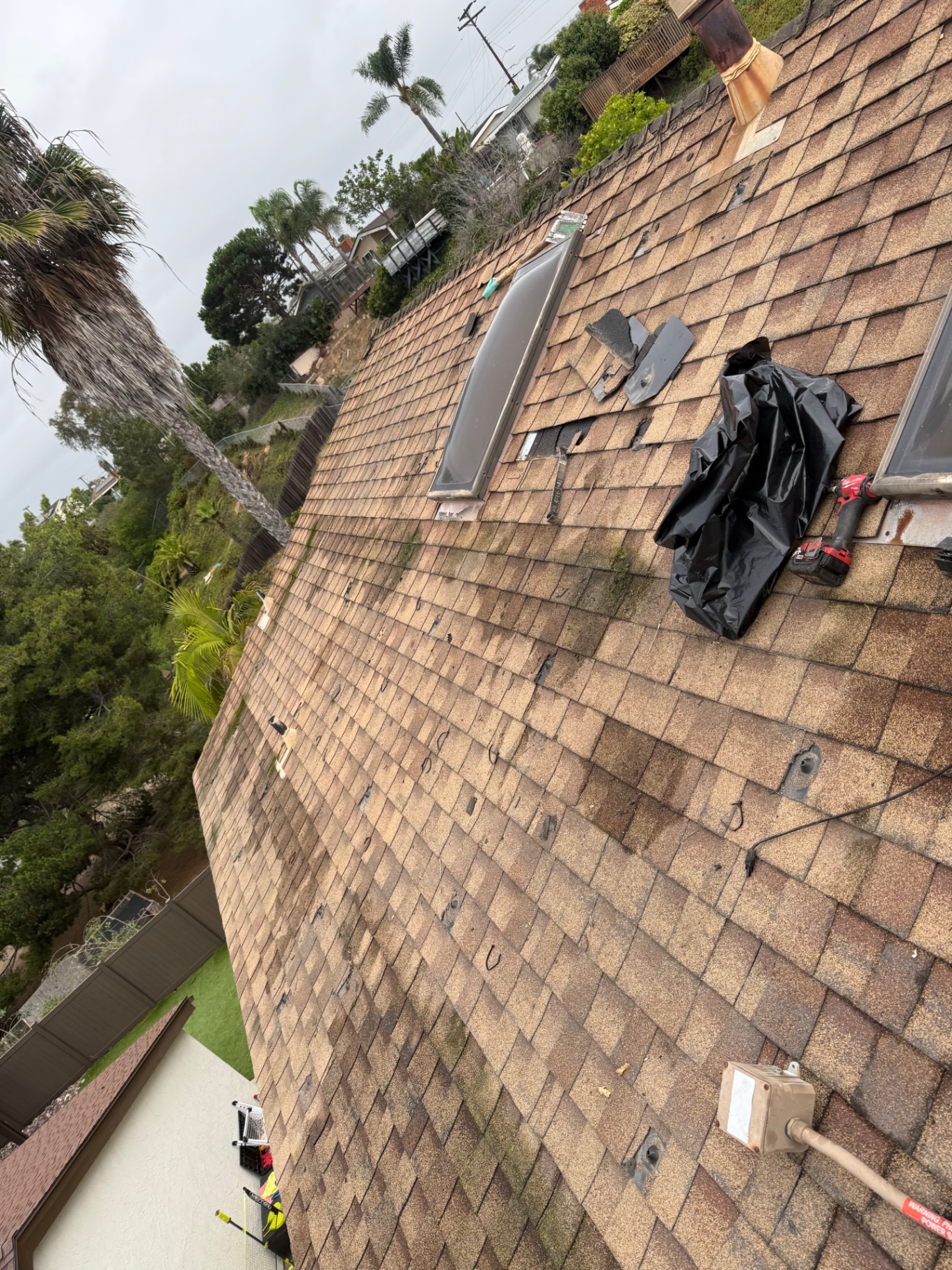 Old asphalt shingle roof during solar mounting hardware removal and complete tear-off