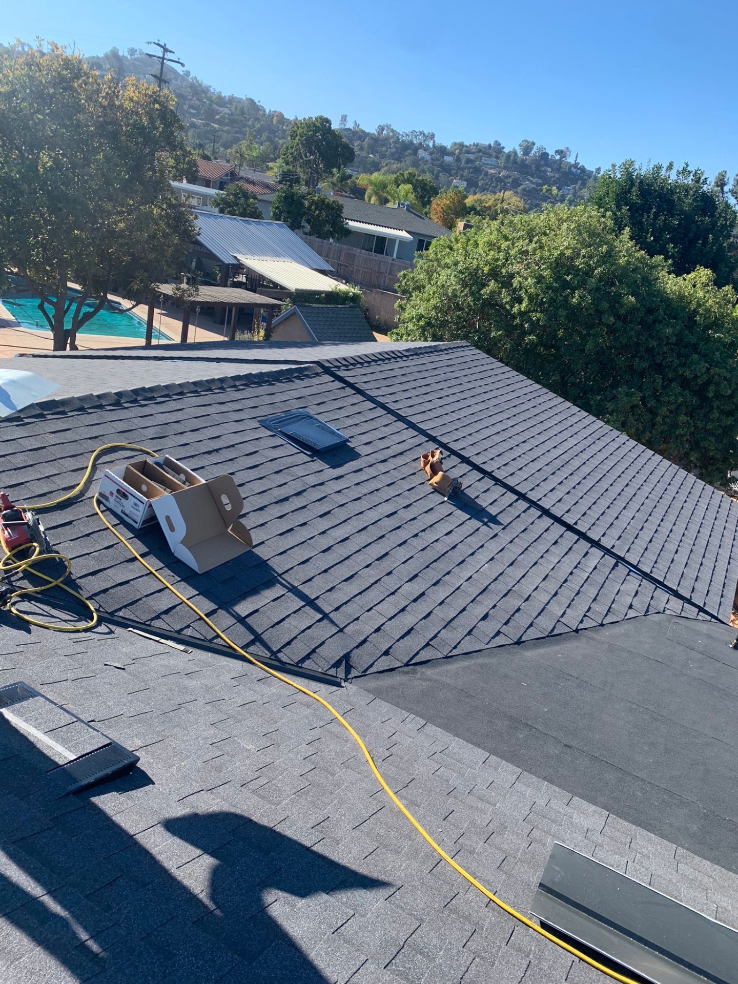 Completed gray architectural shingle hip roof over a San Diego pool home