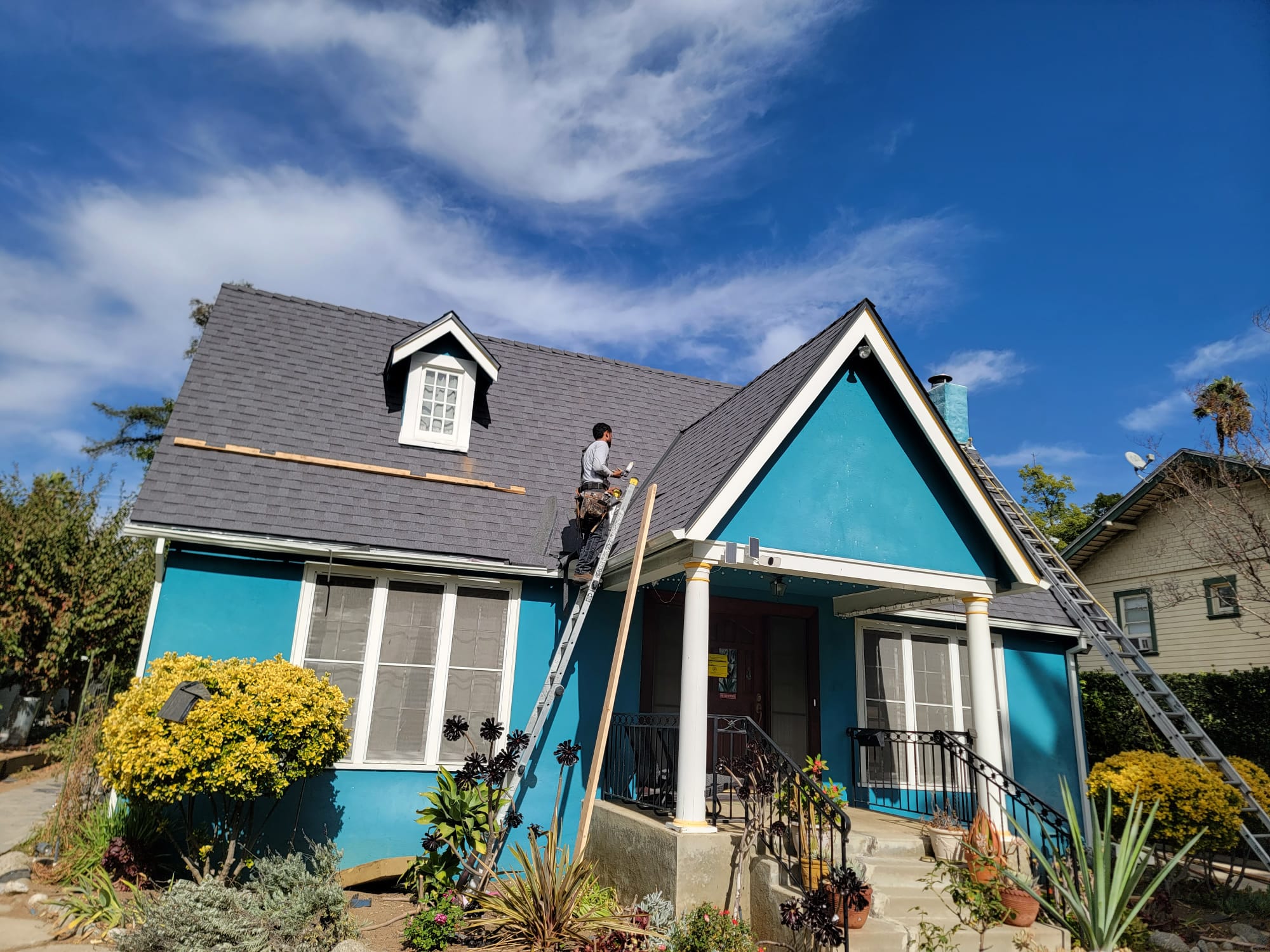 Completed dark architectural shingle roof on a teal craftsman home with dormer window
