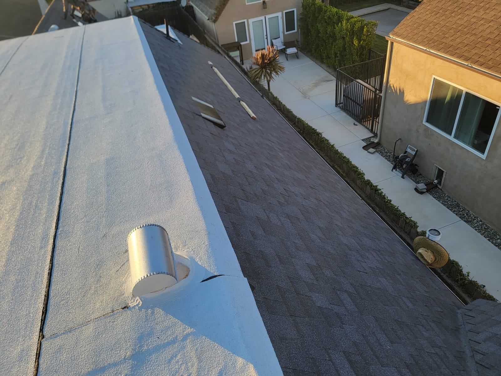Combination roof with white coated flat section adjacent to new dark shingles