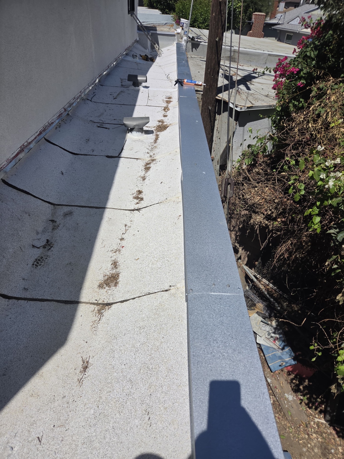 Completed flat roof edge with new coping metal, vents and sealed seams