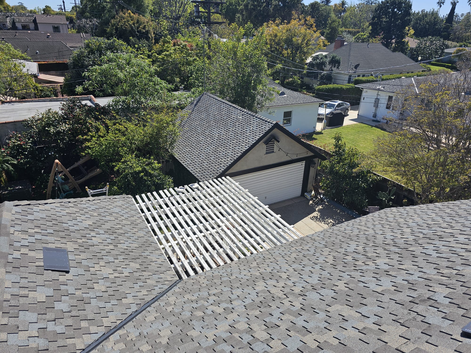Aerial view of a new gray architectural shingle roof beside a patio trellis