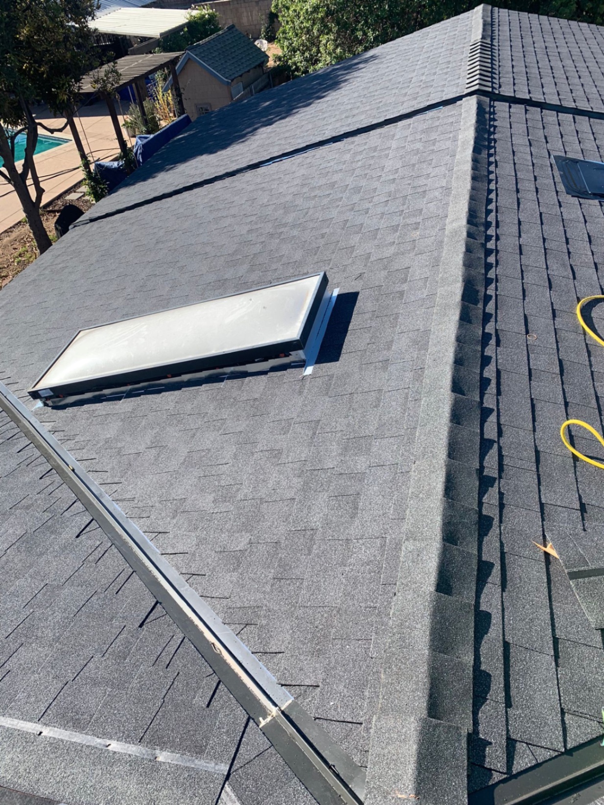 Finished gray architectural shingle roof with re-flashed skylight in San Diego