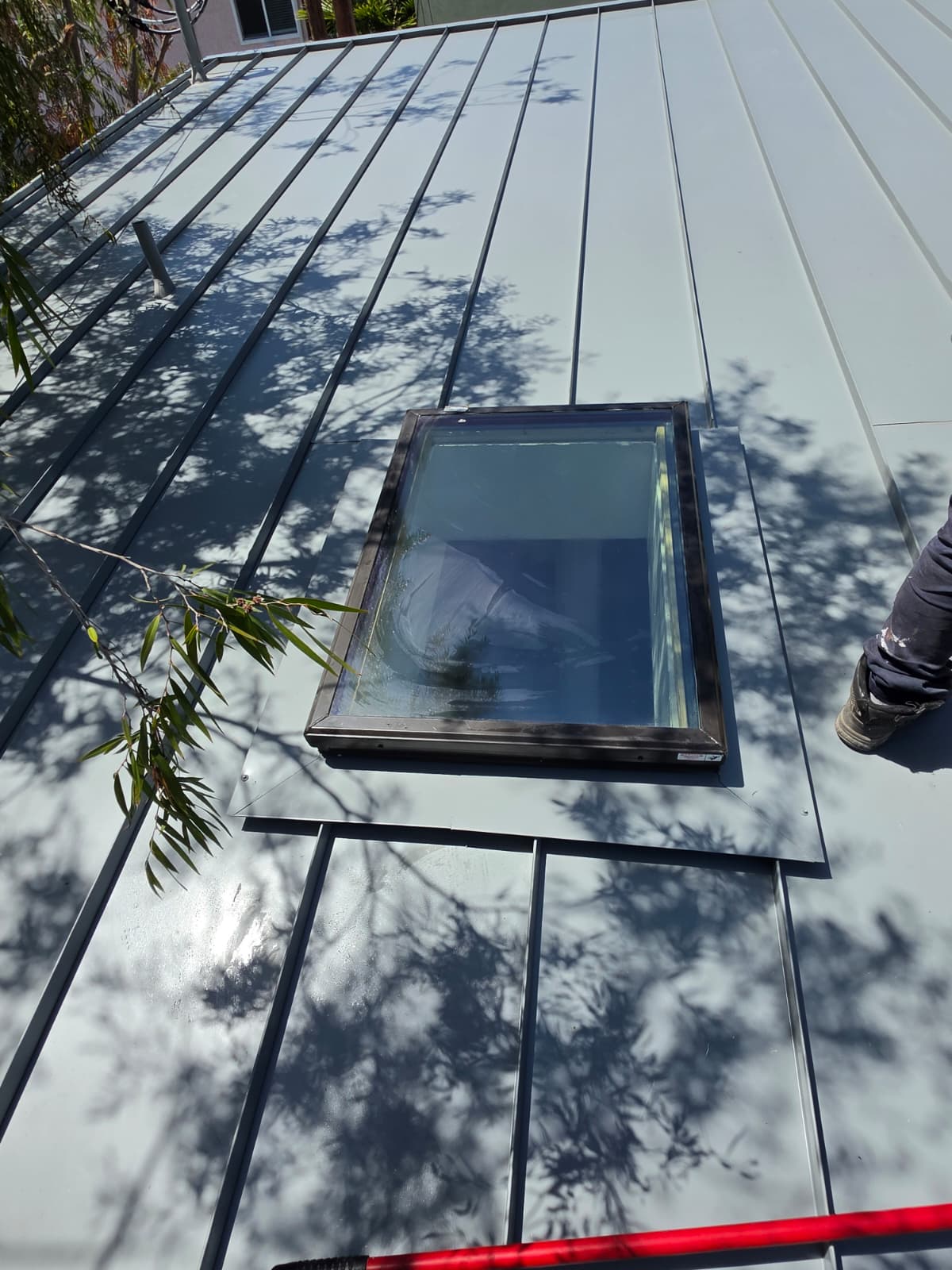 Skylight curb flashed into a standing seam metal roof panel in San Diego