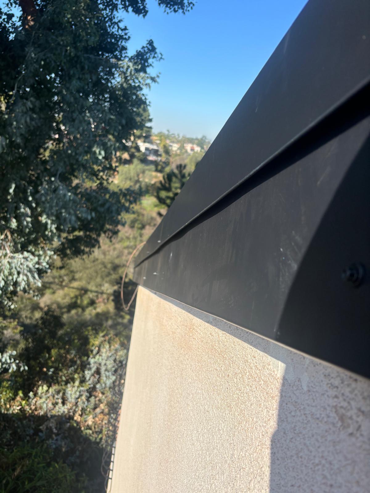 Corner detail of custom metal fascia board wrapping a stucco parapet edge