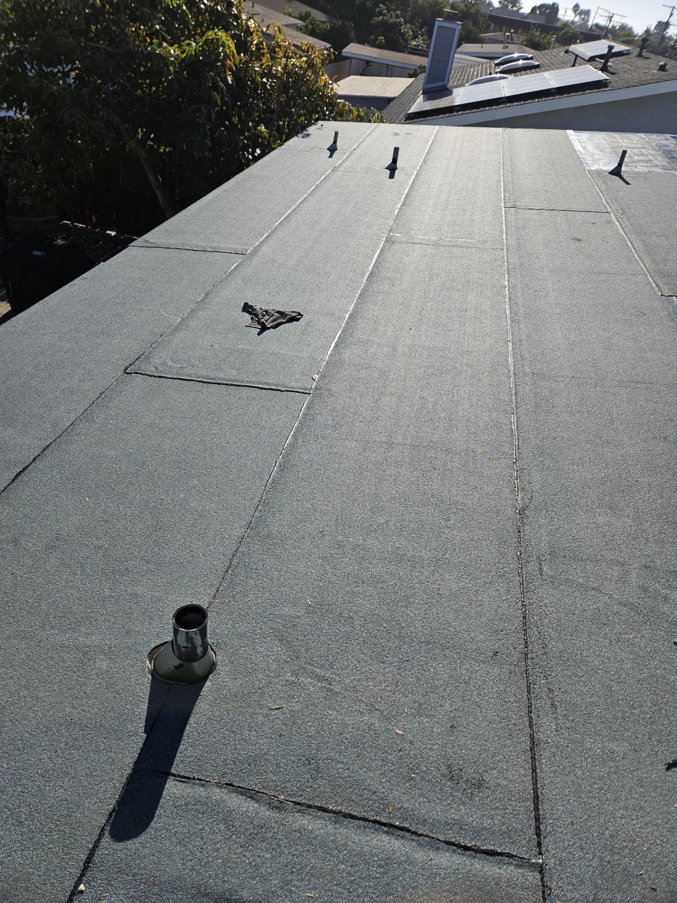 Completed Polyglass torch-down roof with sealed seams and new pipe flashings
