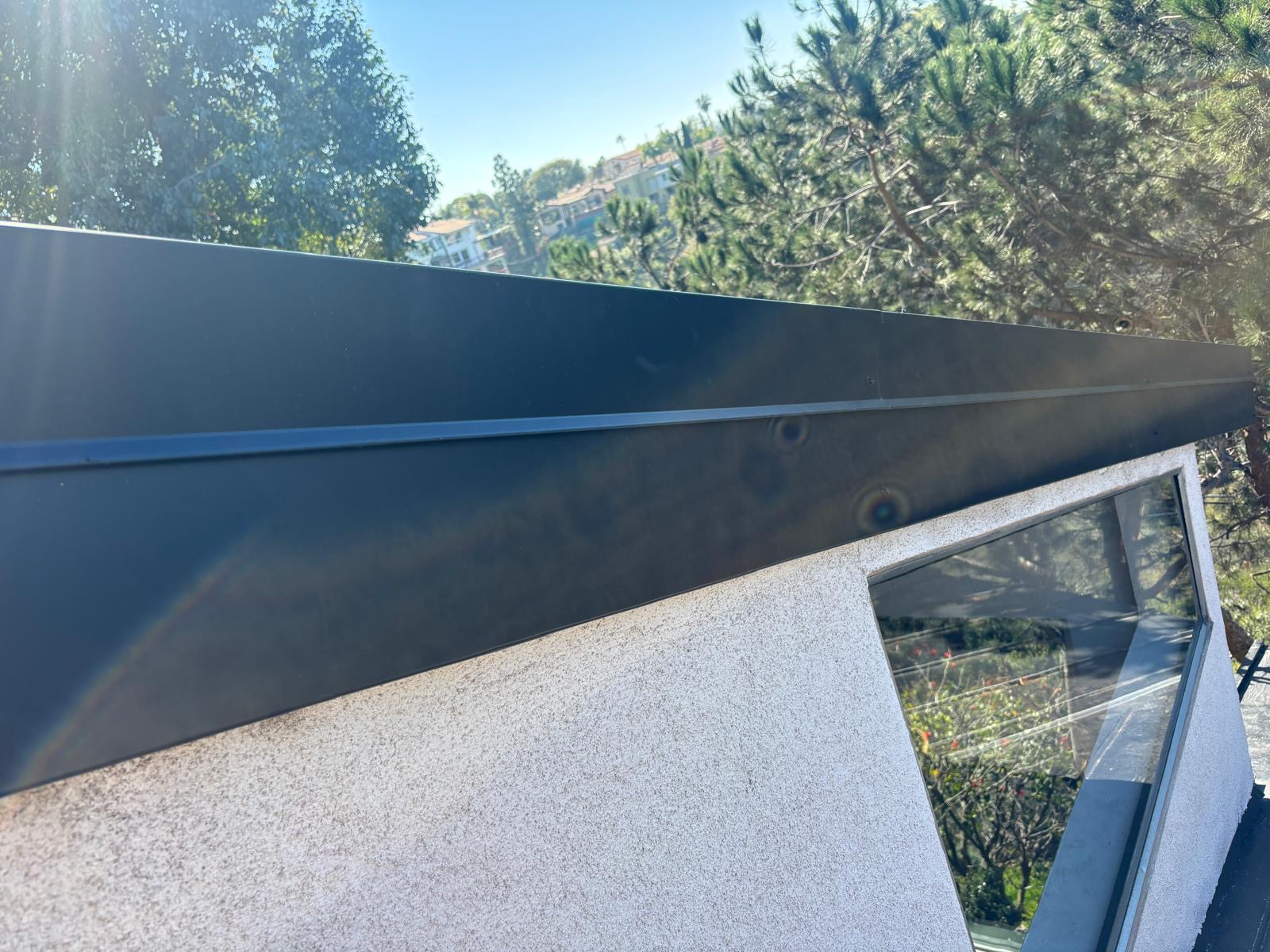 Long run of new dark metal fascia along a hillside home roof edge in San Diego