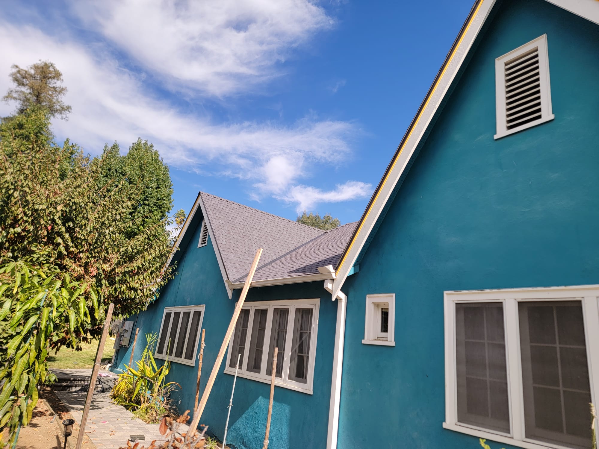 Side elevation of a completed charcoal shingle roof with new white fascia and gutters