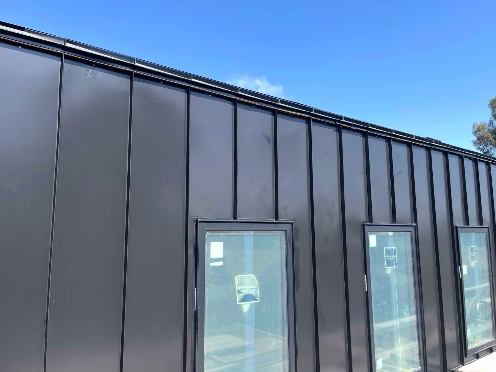Dark bronze standing seam metal roof and wall cladding on a modern California build