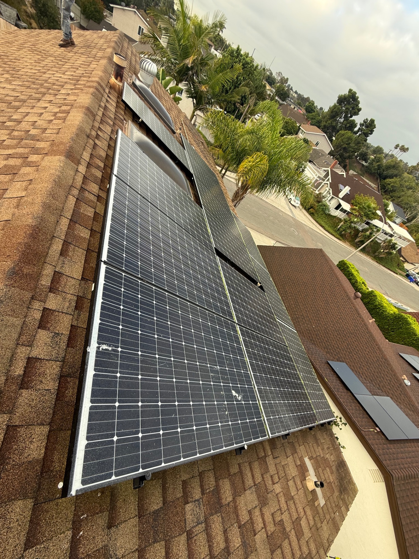 Solar panels installed over an aging asphalt shingle roof before removal in San Diego
