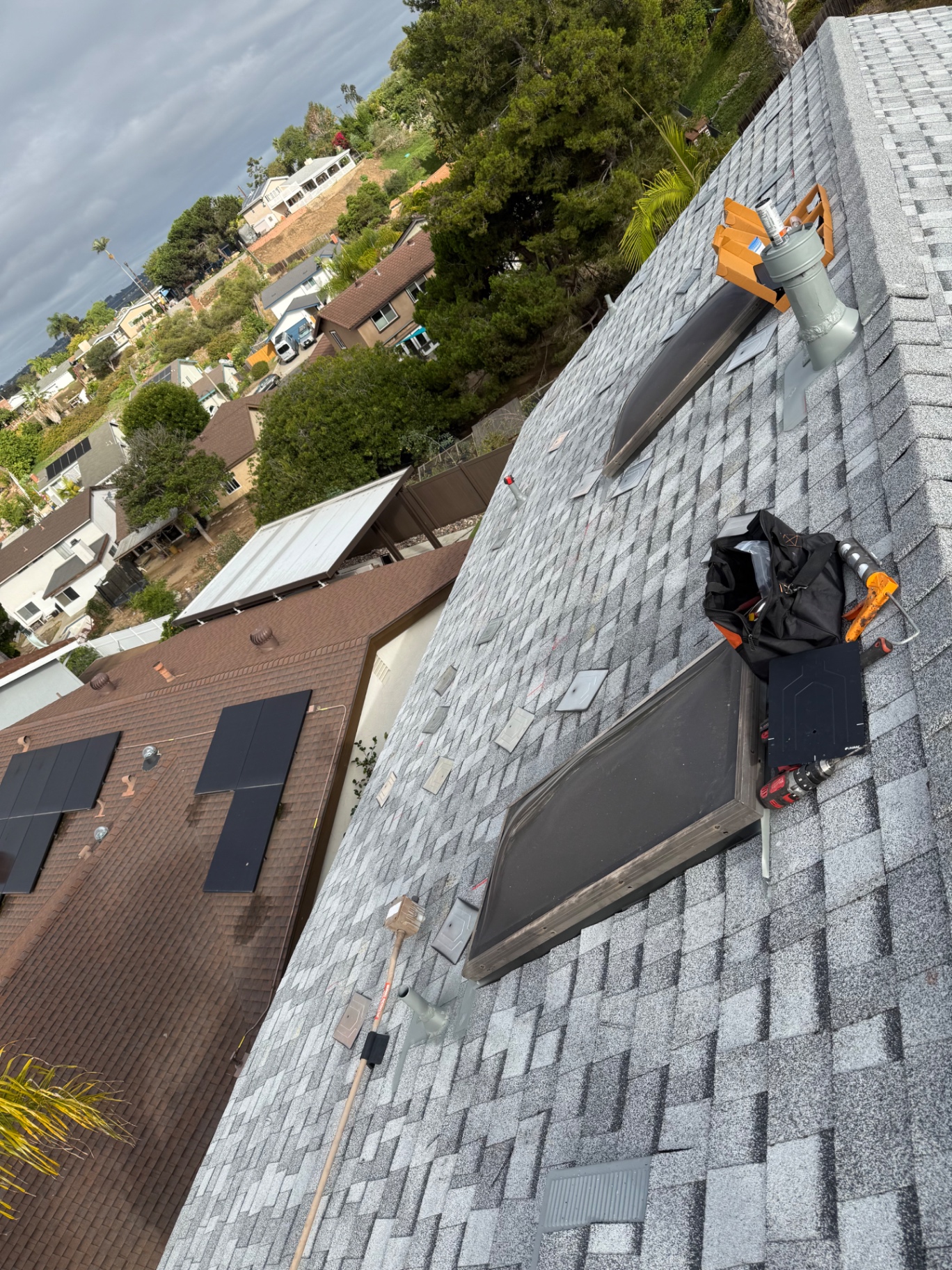 New gray architectural shingle roof with skylights, flashed vents, and solar attachment work