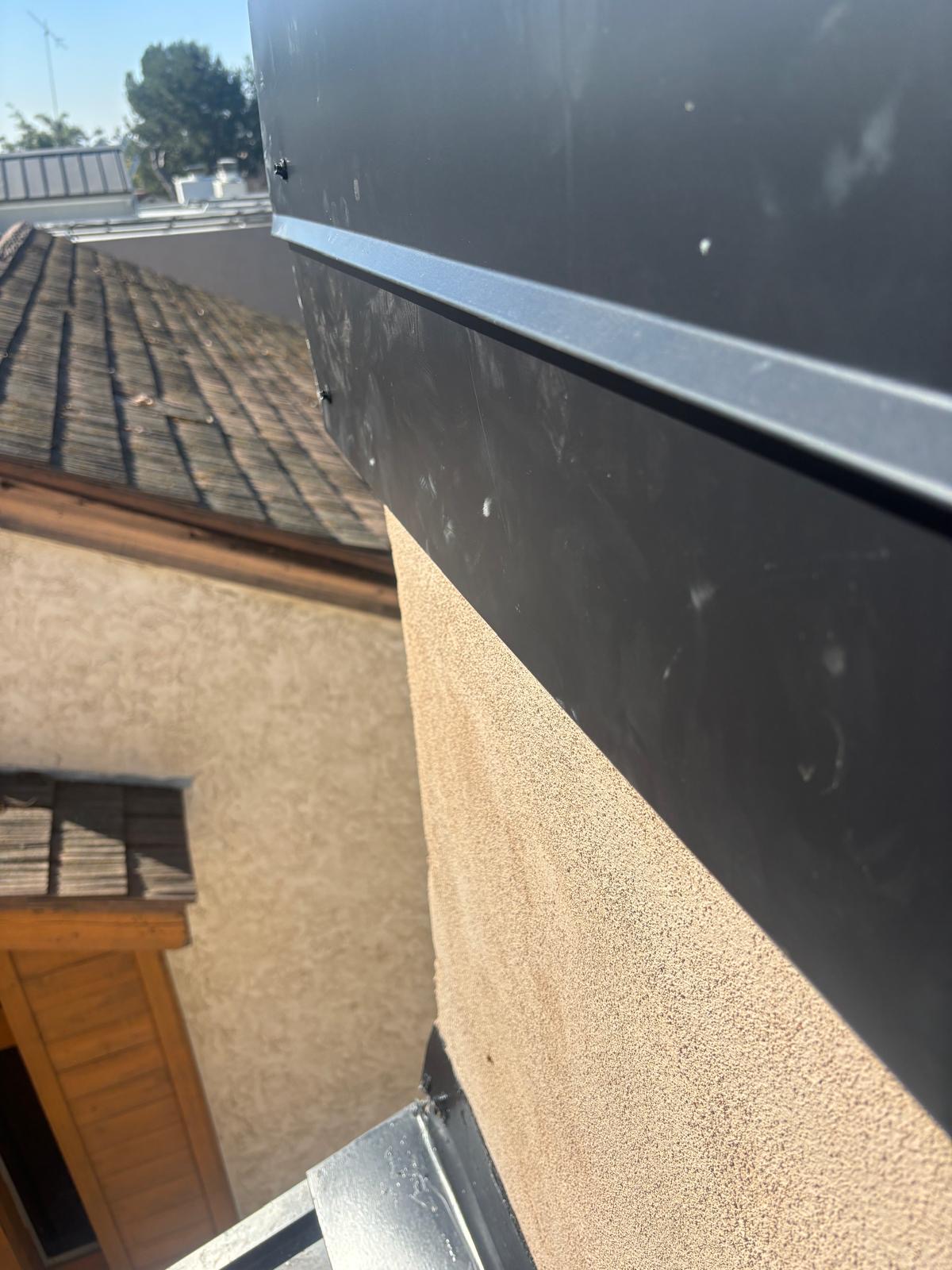 Close view of new metal fascia replacing wood fascia next to an aged wood shake roof